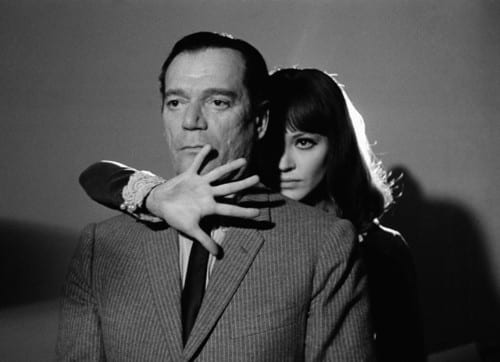 1965, France --- American actor Eddie Constantine and Danish actress and singer Anna Karina on the set of "Alphaville, Une Etrange Aventure de Lemmy Caution" (Alphaville, a Strange Adventure of Lemmy Caution) by her husband French Swiss director, screenwriter and producer Jean-Luc Godard. --- Image by © Georges Pierre/Sygma/Corbis