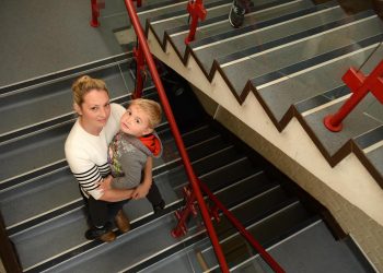 Sharon Arkell with her son Tommy, 3 on the stairs which lead to their council house. See SWNS story SWSTAIRS; Council housing chiefs saw a video of a mum struggling to carry her four-year-old with muscular dystrophy up two flights of stairs – and turned down a request for priority housing because she made it to the top. A panel at South Gloucestershire Council watched the news film of Sharon Mikkelson carrying her son Tommy up the 30 stairs to their second-floor flat in Filton as part of a hearing to decide whether the family qualified to be awarded priority housing status. Young Tommy will soon receive his first wheelchair next week as the muscular dystrophy which is already affecting his body gets worse. The family have asked to be re-homed in a ground floor flat or home, but have not been offered anything suitable.