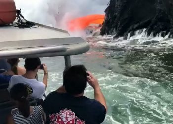 This is the spectacular moment tonnes of molten lava spew from a collapsed volcano into the sea - just yards from boat full of tourists. See SWNS story SWLAVA; Onlookers braved the choppy seas and deadly eruptions taking place at the Kamokuna lava delta in Hawaii since it collapsed on December 31. They were stunned when a red hot stream of 1000c lava suddenly crashed through the side of the black rock - causing an incredible hose pipe effect. Breath-taking footage shows the ''once-in-a-lifetime'' natural phenomenon as hot gunge pours into the sea - solidifying and producing thick clouds of steam. Tour operator Captain Shane Turpin, who shot the footage with guests on his Lava Ocean Tours ship, said: ''This was a real rare sight as the guests watched in awe.