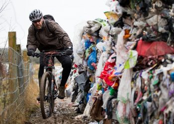 Lee Tanner 49 rides past a mountain of waste such as food products, plastics and paper has been dumped on a cycle path between Biddulph and Brindley Ford, Staffordshire. February 01, 2017.  See NTI story NTIRUBBISH; Police are hunting "industrial fly-tippers" who dumped 50 huge blocks of compressed recyclable rubbish at a beauty spot popular with mountain bikers and walkers. Tens of thousands of discarded plastic bottles, bags and cardboard boxes which had been compacted into 10ft-high cubes were left strewn across the path. Cyclists and walkers were forced to squeeze past the stinking piles of trash after they were discovered on the route between Biddulph and Brindley Ford, Staffs., on Saturday (28/1).  Staffordshire Police and council officials are now investigating in a bid to find out who dumped the rubbish. Dog-walker David Rowe, 66, who discovered the waste, said: "I walked my dog on Friday night and there was nothing there.