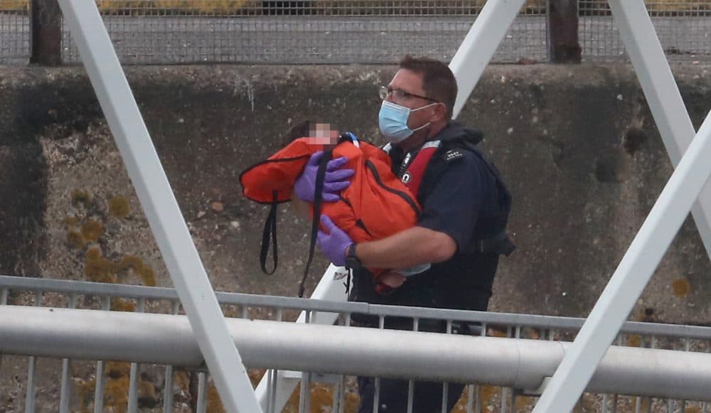 A Border Force officer carries a young child as a group of people thought to be migrants are brought into Dover, Kent, on a Border Force vessel following a number of small boat incidents in the Channel earlier today.