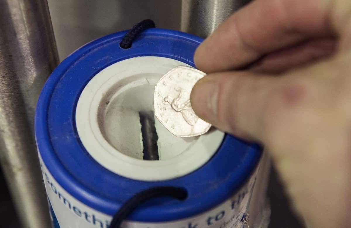 PICTURE POSED BY PHOTOGRAPHER
A coin is dropped into a charity collection container in London.