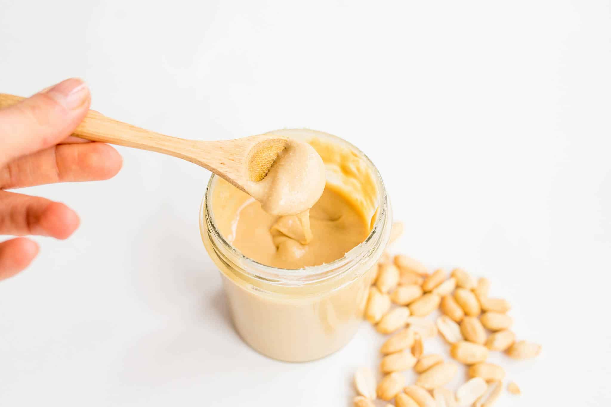Homemade peanut butter in glass jar with hand and wooden spoon Photo: Marco Verch Professional Photographer / Flickr