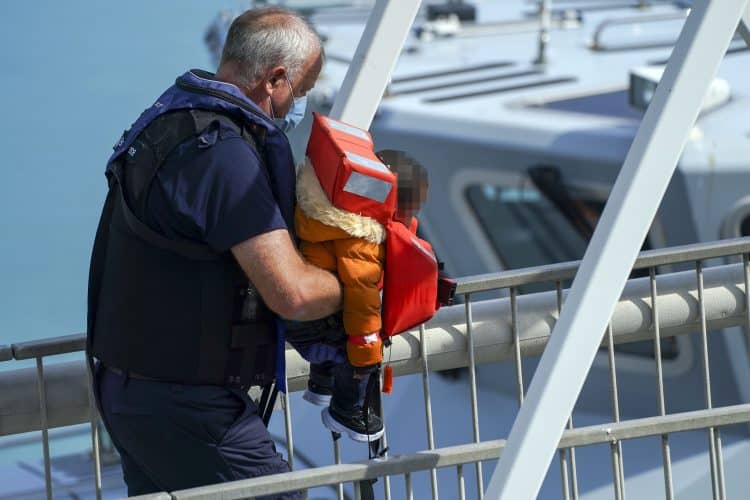 EDITORS NOTE Children's faces have been pixelated as the PA Picture Desk has been unable to gain the necessary permission to photograph a child under 16 on issues involving their welfare. A young child is carried ashore as a group of people thought to be migrants are brought in to Dover, Kent, by Border Force officers, following a small boat incident in the Channel. Picture date: Sunday August 15, 2021.