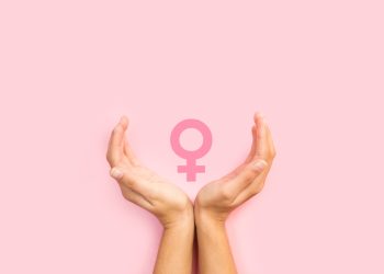 Woman hands protecting female sign on a pink background