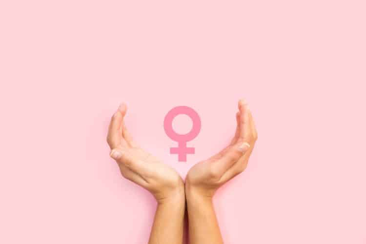 Woman hands protecting female sign on a pink background